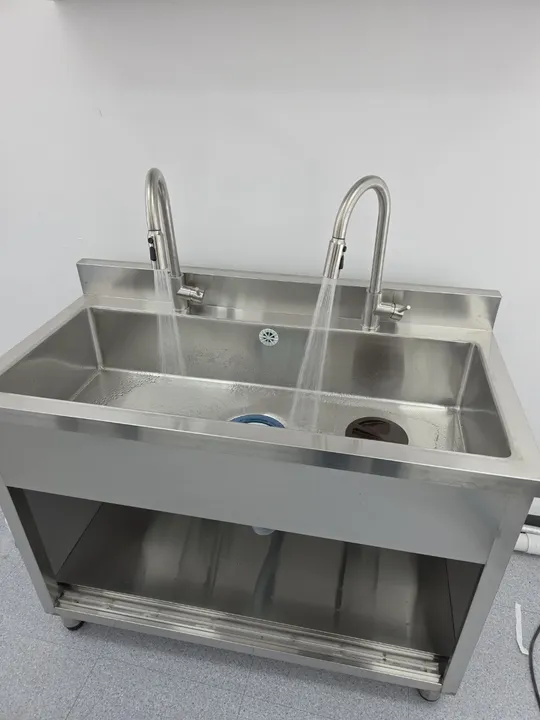 빈 벽면 배관 자리에 수전 2개를 갖춘 2조 개수대가 제작·설치되고 통수 확인 중인 모습